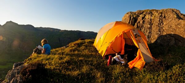 Woman reading outside tent